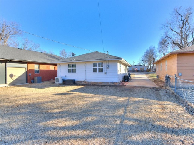 back of property featuring central air condition unit, driveway, and fence
