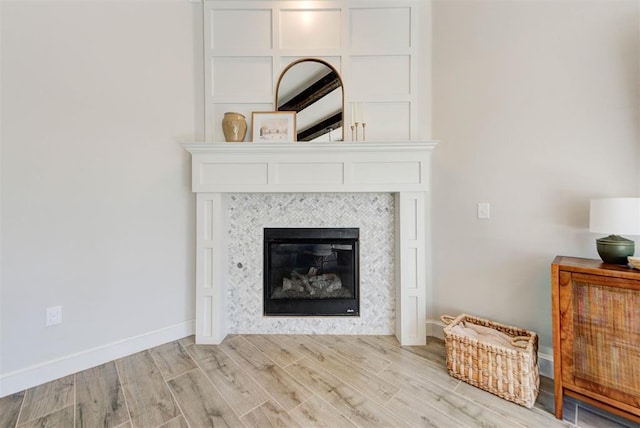 unfurnished living room with baseboards, a fireplace, and light wood-style floors