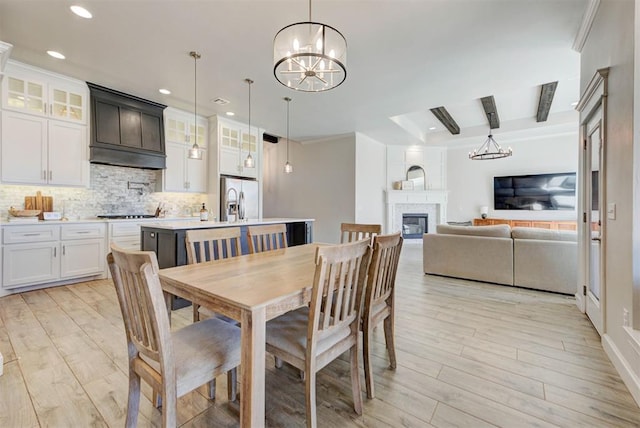 dining area with a chandelier, a glass covered fireplace, light wood-style flooring, and recessed lighting