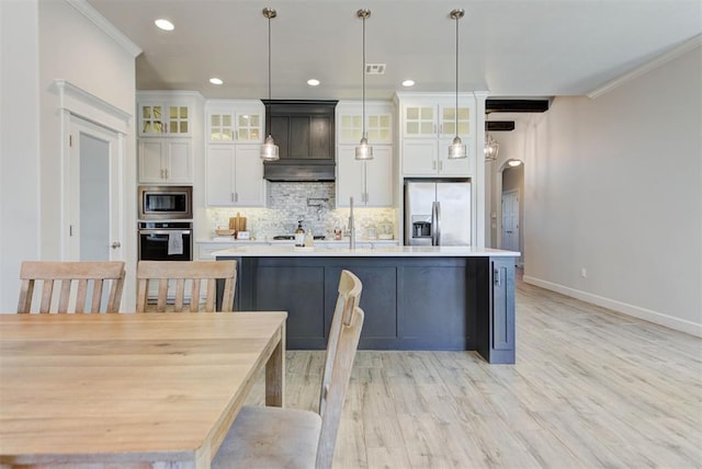 kitchen featuring an island with sink, ornamental molding, stainless steel appliances, and backsplash