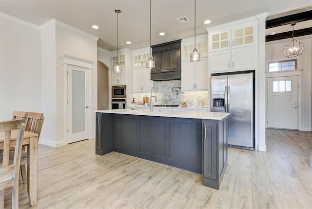 kitchen with arched walkways, visible vents, light countertops, appliances with stainless steel finishes, and decorative backsplash