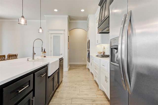 kitchen featuring light countertops, appliances with stainless steel finishes, white cabinets, a sink, and light wood-type flooring