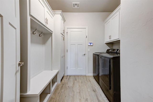 mudroom featuring light wood finished floors, washer and clothes dryer, and visible vents