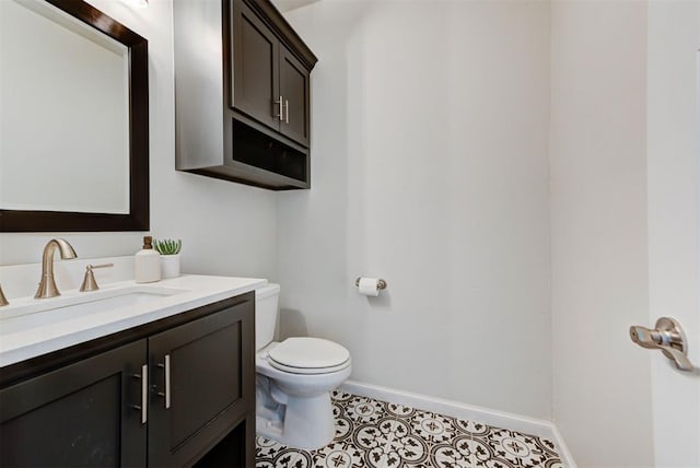 half bathroom with toilet, tile patterned floors, vanity, and baseboards