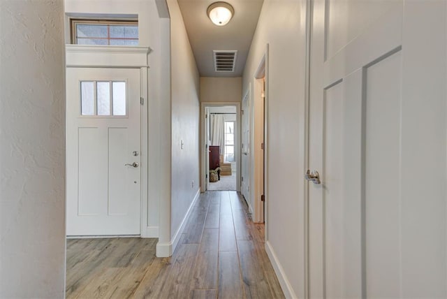 entrance foyer with a textured wall, light wood-type flooring, visible vents, and baseboards