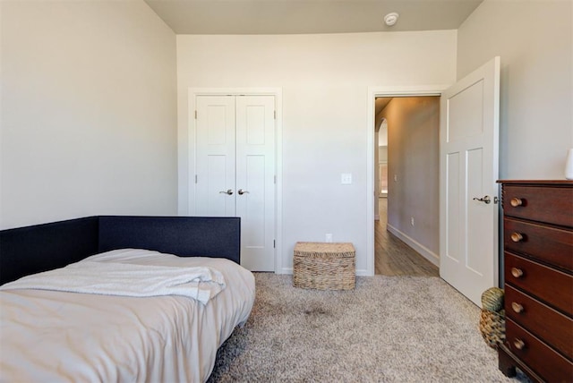 carpeted bedroom featuring a closet and baseboards