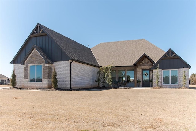 view of front of home featuring brick siding, board and batten siding, and a shingled roof