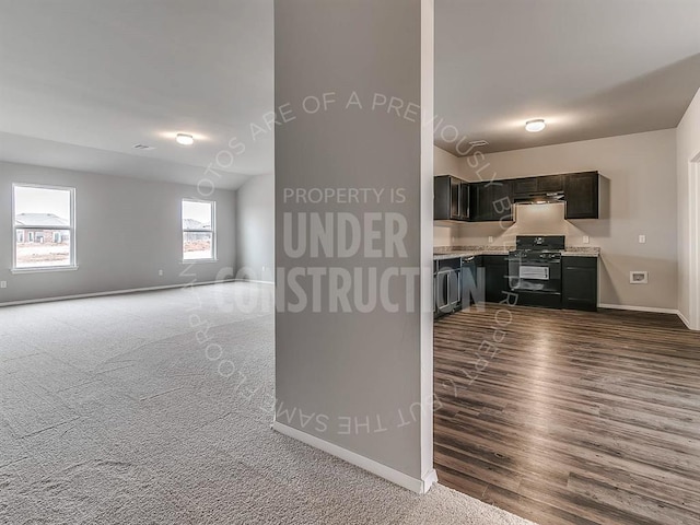 kitchen with black range with gas cooktop, baseboards, open floor plan, light countertops, and dark colored carpet