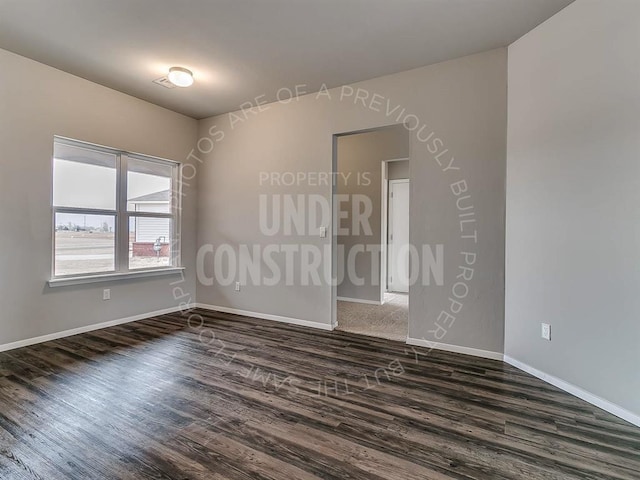 unfurnished room featuring baseboards and dark wood-style flooring