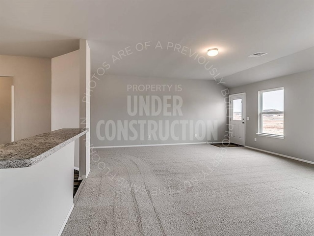 carpeted spare room with visible vents and baseboards