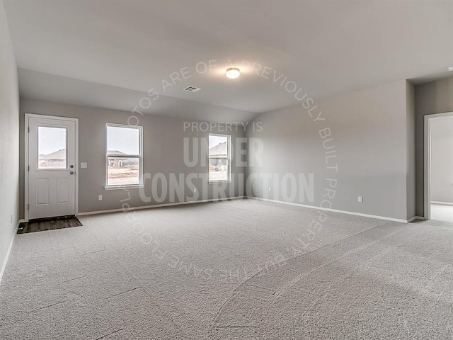 spare room with carpet floors, visible vents, and baseboards