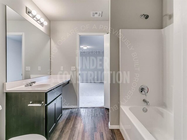 full bath featuring wood finished floors, vanity, visible vents, baseboards, and shower / washtub combination