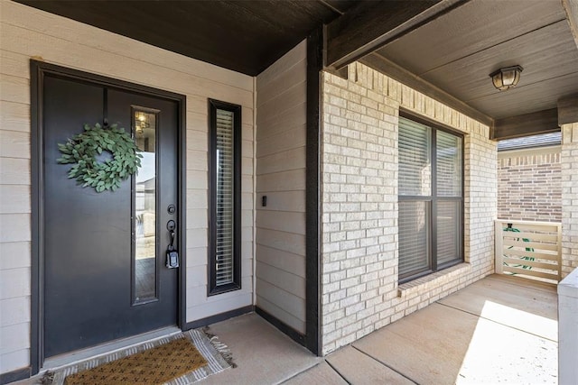 entrance to property with covered porch and brick siding