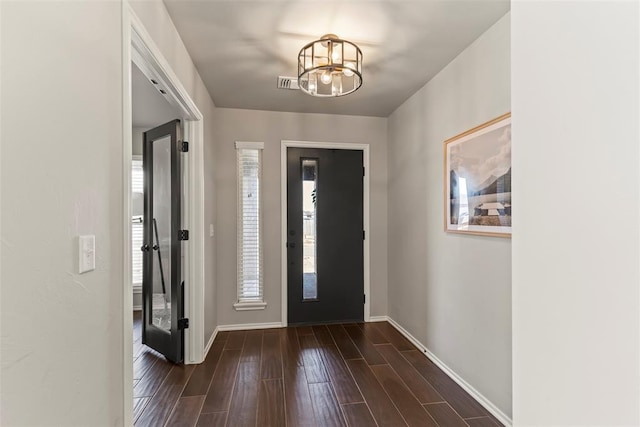 entryway with dark wood-style flooring, visible vents, a notable chandelier, and baseboards