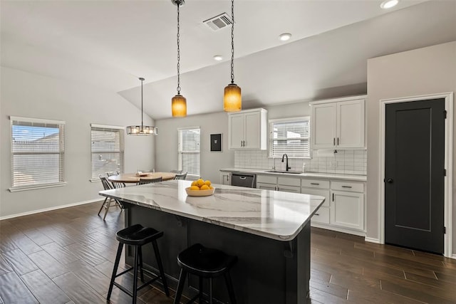 kitchen with a sink, visible vents, dark wood-style floors, vaulted ceiling, and dishwasher