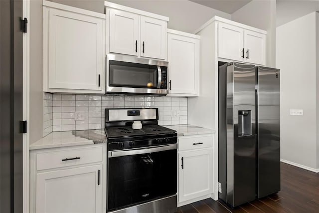 kitchen featuring light stone counters, dark wood-style flooring, stainless steel appliances, tasteful backsplash, and white cabinetry