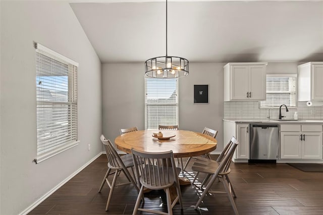 dining space featuring lofted ceiling, dark wood-style flooring, an inviting chandelier, and baseboards