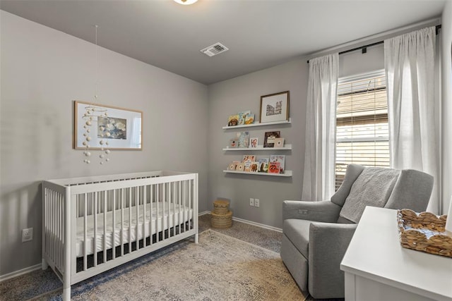 bedroom featuring a crib, carpet flooring, visible vents, and baseboards