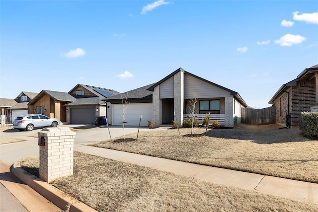 view of front facade with an attached garage, fence, concrete driveway, and brick siding