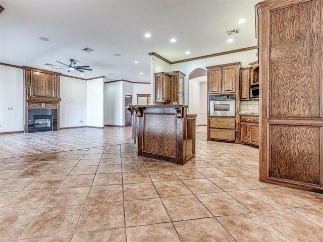 kitchen with arched walkways, light tile patterned floors, stainless steel appliances, visible vents, and open floor plan