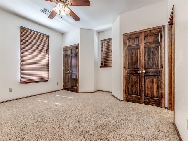 unfurnished bedroom with carpet floors, visible vents, ceiling fan, and baseboards