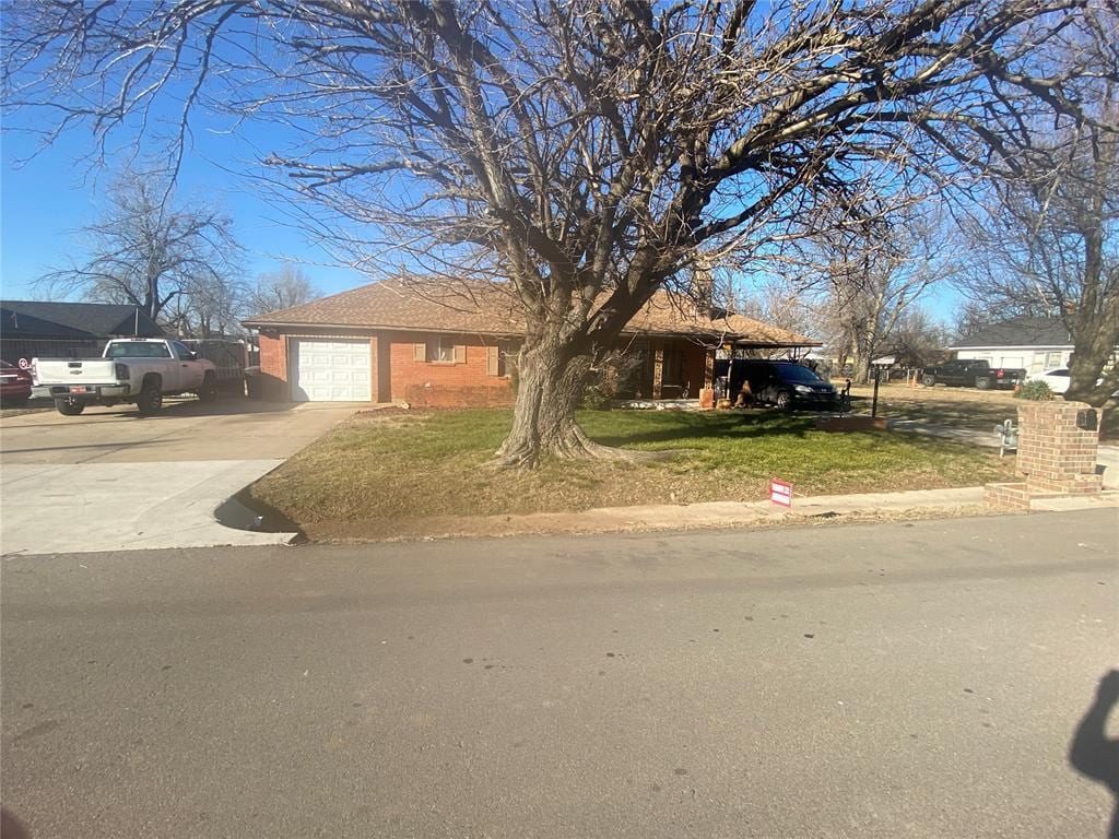 view of front of house with a garage, driveway, brick siding, and a front yard