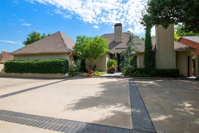 view of front of house with a shingled roof and a chimney