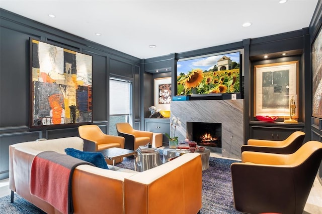 sitting room with recessed lighting, a decorative wall, and a premium fireplace