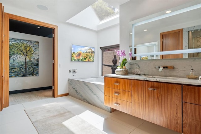 full bath with a garden tub, tile patterned flooring, a skylight, vanity, and tasteful backsplash