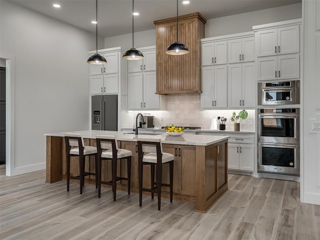 6409 NW 153rd St, Edmond, OK 73013 - kitchen featuring appliances with stainless steel finishes, a sink, light countertops, decorative backsplash, and a center island with sink