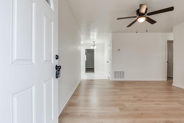 unfurnished room with a ceiling fan, light wood-type flooring, visible vents, and baseboards