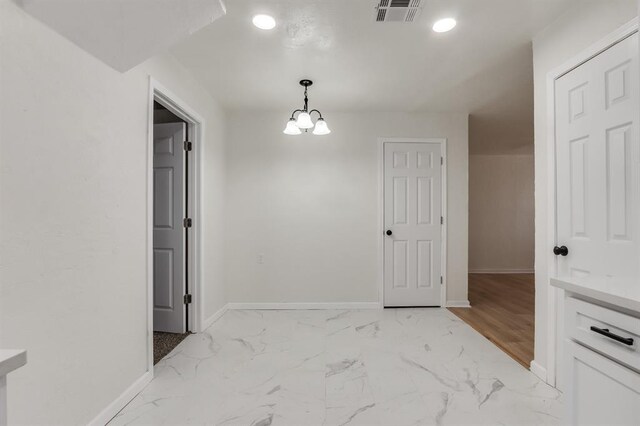 unfurnished dining area with marble finish floor, baseboards, visible vents, and a chandelier