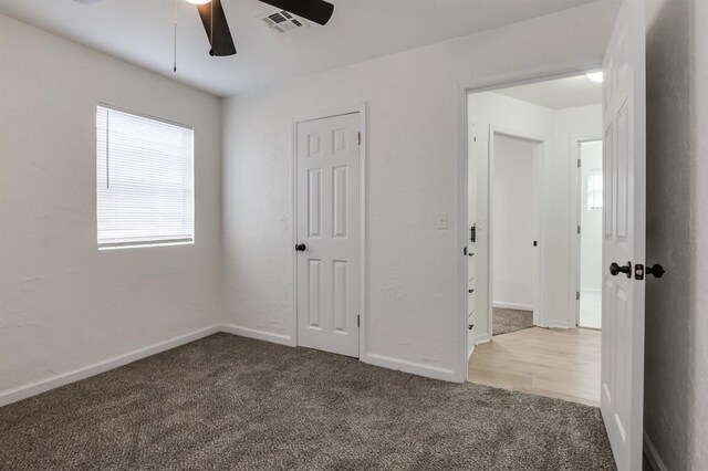 unfurnished bedroom with ceiling fan, carpet floors, visible vents, and baseboards