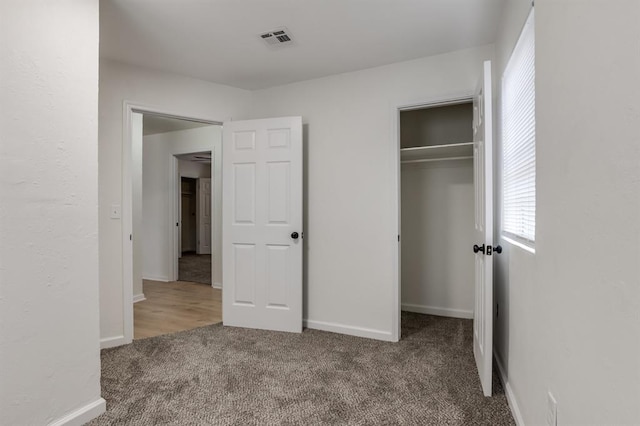 unfurnished bedroom with baseboards, carpet, visible vents, and a closet