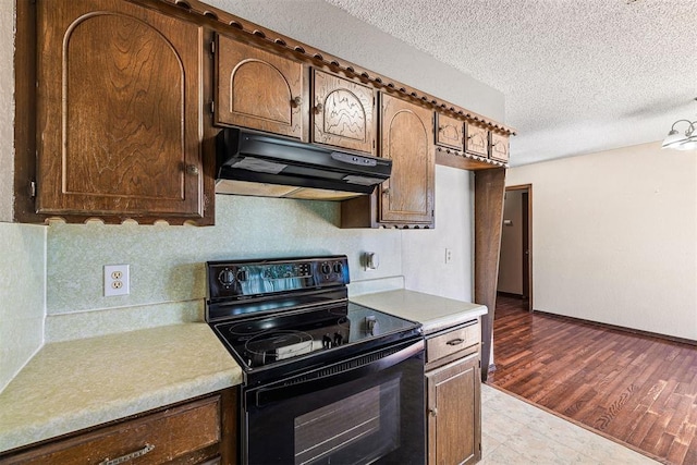 kitchen featuring under cabinet range hood, black / electric stove, light countertops, and a textured ceiling