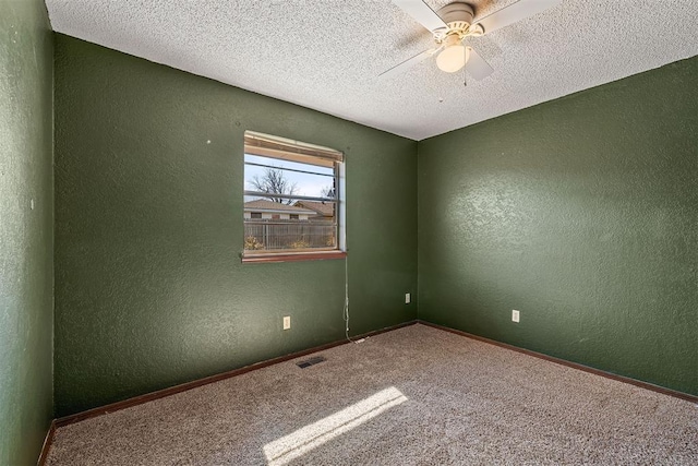 carpeted empty room with visible vents, a textured wall, ceiling fan, a textured ceiling, and baseboards