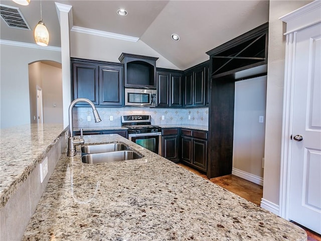 kitchen with arched walkways, stainless steel appliances, visible vents, decorative backsplash, and a sink