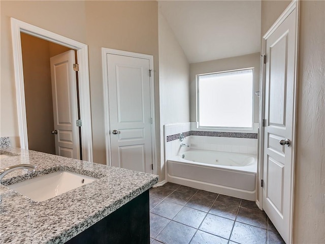 full bath featuring a whirlpool tub, tile patterned flooring, lofted ceiling, and vanity