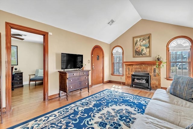 living area featuring baseboards, visible vents, vaulted ceiling, and wood finished floors