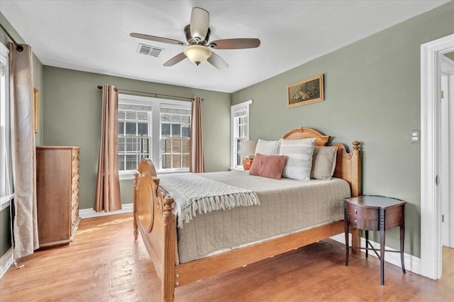 bedroom featuring baseboards, ceiling fan, visible vents, and light wood-style floors