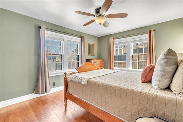 bedroom with ceiling fan, wood finished floors, and baseboards