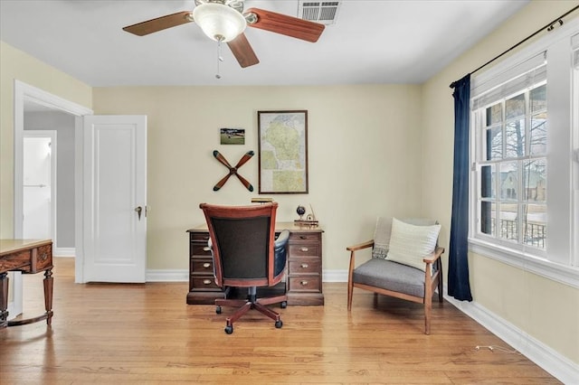 office with a ceiling fan, visible vents, light wood-style flooring, and baseboards