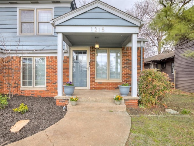 property entrance with brick siding and a porch