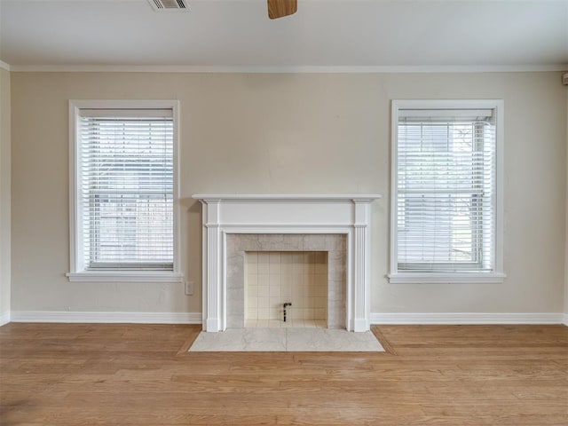 unfurnished living room with plenty of natural light, ornamental molding, and wood finished floors