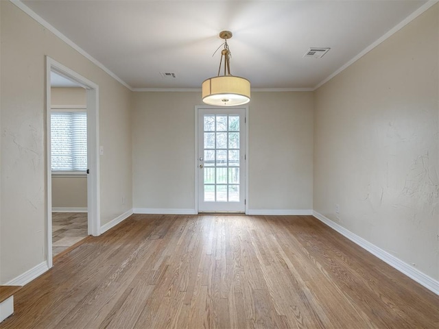 spare room with light wood finished floors, visible vents, and ornamental molding