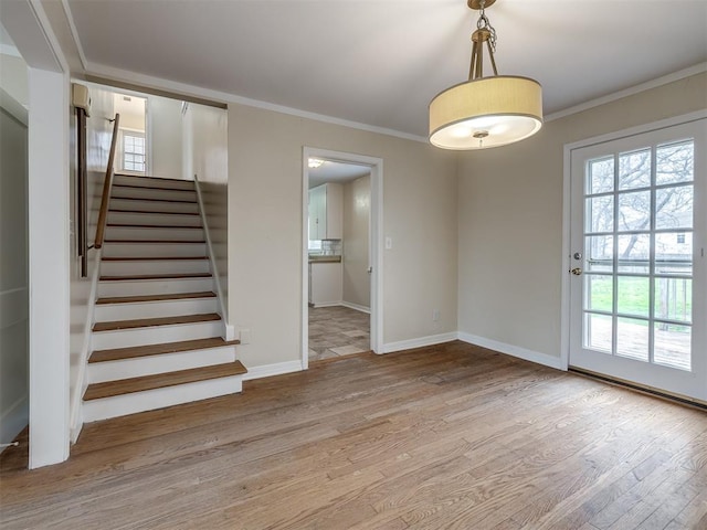 interior space with stairs, baseboards, light wood-style floors, and crown molding