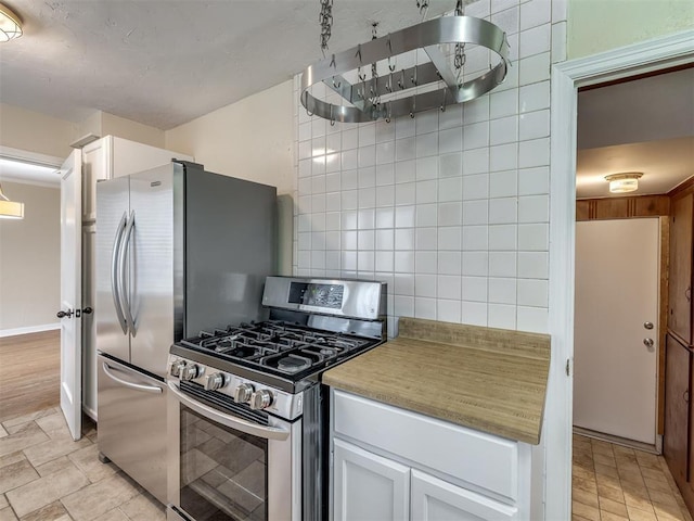 kitchen featuring decorative backsplash, light countertops, white cabinets, and stainless steel range with gas cooktop