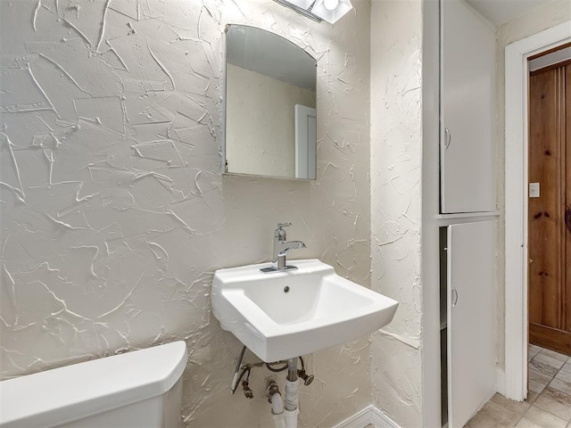 bathroom featuring toilet and a textured wall