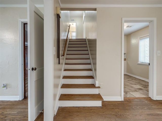 stairs with visible vents, baseboards, and wood finished floors