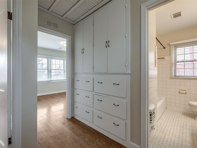 hall with tile walls, visible vents, and a wealth of natural light